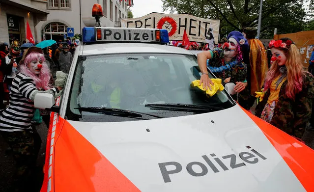 Protesters dressed as clowns wipe the windows of a Swiss police car before a May Day demonstration in Zurich, Switzerland May 1, 2018. (Photo by Arnd Wiegmann/Reuters)