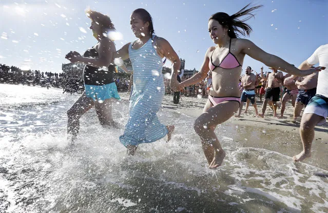 People run into the cold ocean during the Sons of Ireland's annual New Year's Day Polar Bear Plunge on a sunny, but frigid Thursday, January 1, 2015, in Asbury Park, N.J. (Photo by Mel Evans/AP Photo)