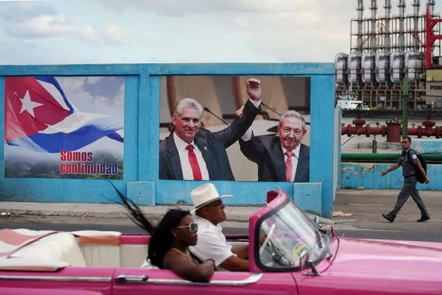 A vintage car passes by an image of Cuba's former President Raul Castro and Cuba's President and First Secretary of the Communist Party Miguel Diaz-Canel beside a sign that reads: “We are continuity”, in Havana, Cuba on April 17, 2023. (Photo by Alexandre Meneghini/Reuters)