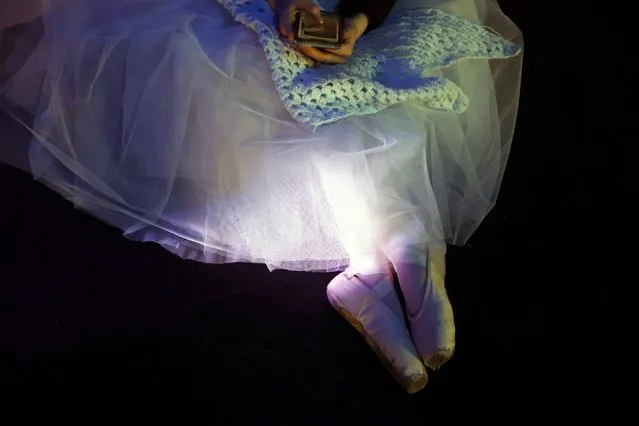 A ballerina from Kyiv City ballet looks at her phone during the dress rehearsal for the opening night gala performance at York Theatre Royal in York, Britain on March 30, 2023. (Photo by Lee Smith/Reuters)