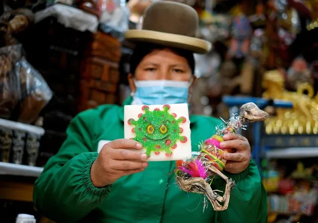 Victoria Acarapi holds a figure of the coronavirus and a llama fetus as part of an offering during the Pachamama (Mother Earth) month at the witches market in La Paz, Bolivia on August 1, 2020. (Photo by David Mercado/Reuters)
