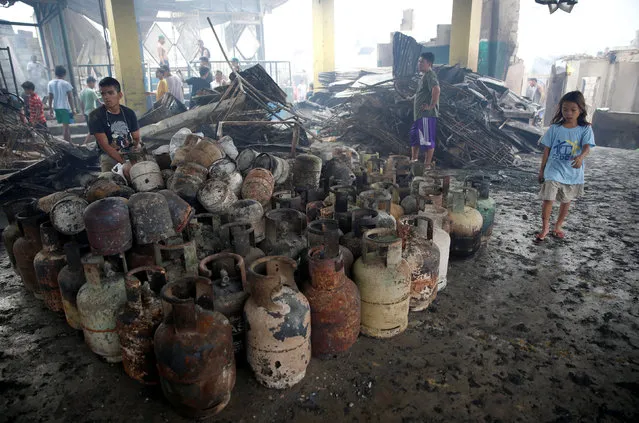 A resident sits near partially burnt LPG cylinders recovered from his family's shop, after a fire in the residential district of Addition Hills in Mandaluyong, Metro Manila, Philippines, November 14, 2016. (Photo by Erik De Castro/Reuters)