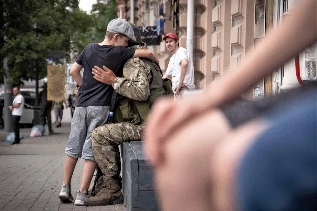 A young boy hugs a member of Wagner group in Rostov-on-Don, on June 24, 2023. (Photo by Roman Romokhov/AFP Photo)