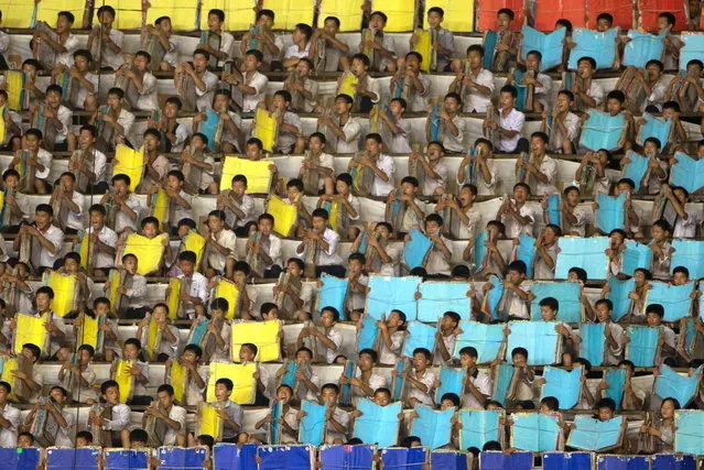 Performers warm up prior to an “Arrirang Festival mass games display” at the 150,000-seat Rungnado May Day Stadiumin Pyongyang on July 26, 2013. Arrirang performances feature some 100,000 participants to create a 'synchronized socialist-realist spectacular in a 90 minute display of gymnastics, dance, acrobatics, and dramatic performance, in a highly politicized package' according to the China-based North Korean travel company Koryo Tours. North Korea is preparing to mark the 60th anniversary of the end of the Korean War which ran from 1950 to 1953, with a series of performances, festivals, and cultural events culminating with a large military parade. (Photo by Ed Jones/AFP Photo)