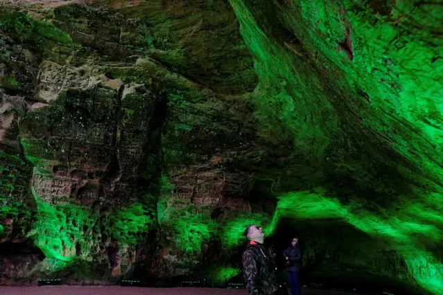 People visit the Gutman's cave, the largest in the Baltic countries, which is illuminated in green during Ireland's annual Global Greening initiative to mark St. Patrick's Day in Sigulda, Latvia on March 16, 2021. (Photo by Ints Kalnins/Reuters)