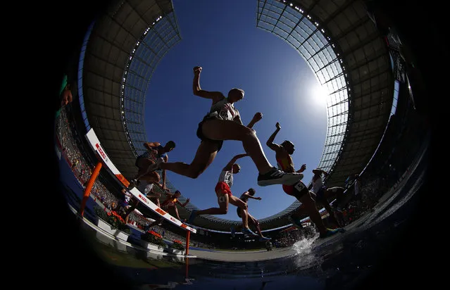 Athletes clear the water in a men's 3000-meter steeplechase heat at the European Athletics Championships at the Olympic stadium in Berlin, Germany, Tuesday, August 7, 2018. (Photo by Matthias Schrader/AP Photo)