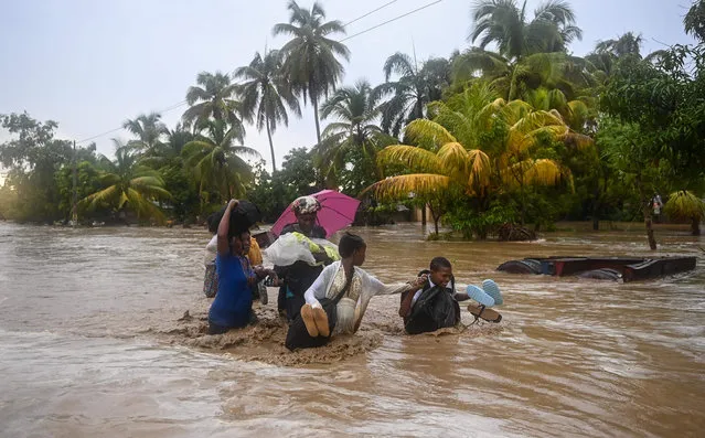 Residents cross the submerged Route Nationale 2 at L'Acul in the Arrondissement of Léogâne 23 mi (or 37 km) west of Port-au-Prince, Haiti, June 3, 2023, during heavy rains (Photo by Richard Pierrin/AFP Photo)
