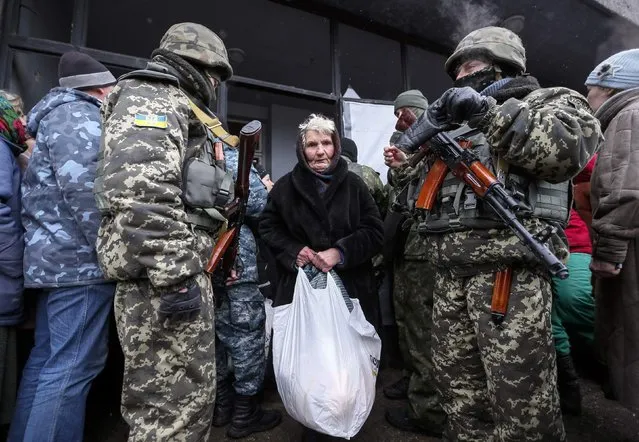 A woman carries a bag of humanitarian aid past Ukrainian servicemen in Debaltseve, eastern Ukraine, February 6, 2015. (Photo by Gleb Garanich/Reuters)