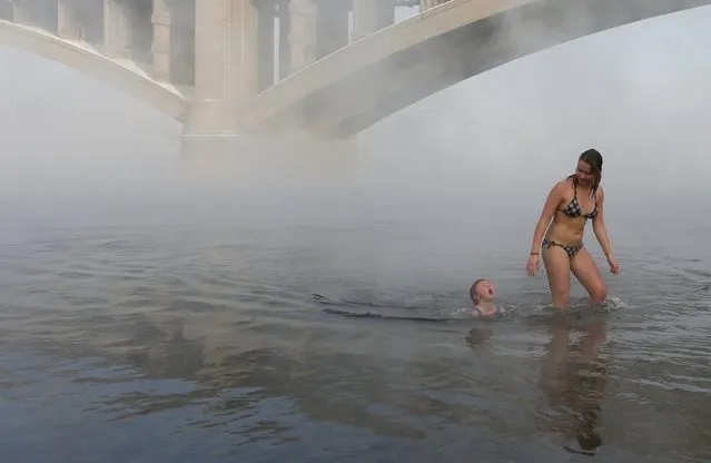 Liza Broverman, 6, and her sister Yulia Klimenkova, 16, members of the Cryophile winter swimmers club, bathe in the icy water of the Yenisei River in the Siberian city of Krasnoyarsk, Russia, November 15, 2015. (Photo by Ilya Naymushin/Reuters)