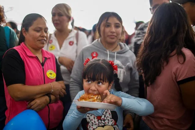 A girl bites a piece of a giant sandwich as people participate in an event to set a new record for the longest sandwich ever made, measuring 75.20 meters long, in Mexico City, Mexico.on August 2, 2023. (Photo by Raquel Cunha/Reuters)