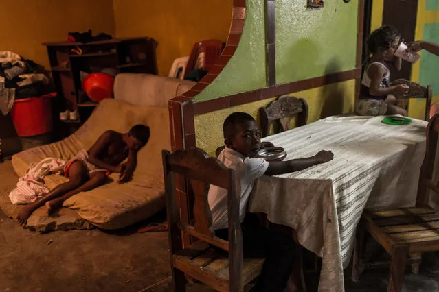In this November 8, 2016 photo, children from the Marval family eat breakfast before going to school in Punta de Araya, Sucre state, Venezuela. After a pirate gang threatened to kill the entire Marval family, some of the clan started keeping their children home from school. Some also stopped going to the state-run hospital because the area is controlled by the gang leader who threatened them. (Photo by Rodrigo Abd/AP Photo)