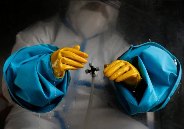 A health worker wearing personal protective equipment (PPE) sanitizes his gloves before taking a polymerase chain reaction (PCR) test from a mobile swab collection vehicle, amid the major second wave of the coronavirus disease (COVID-19) in Kathmandu, Nepal on May 19, 2021. (Photo by Navesh Chitrakar/Reuters)