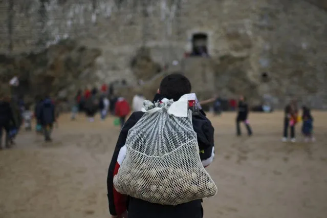 A man carries a net with shellfish during a record low tide in Saint Malo, western France, March 21, 2015. (Photo by Stephane Mahe/Reuters)