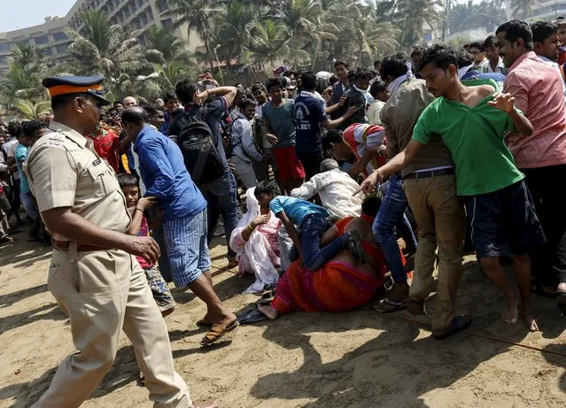 People fall as they are pushed back by policemen from gathering around the carcass of a dead whale on a beach along the Arabian Sea in Mumbai, India, January 29, 2016. (Photo by Danish Siddiqui/Reuters)