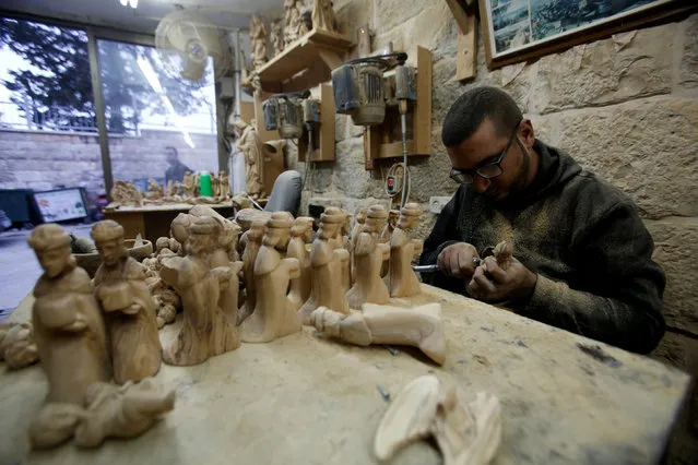 A Palestinian worker carves figurines to be sold during Christmas, in the West Bank town of Bethlehem December 23, 2016. (Photo by Mussa Qawasma/Reuters)