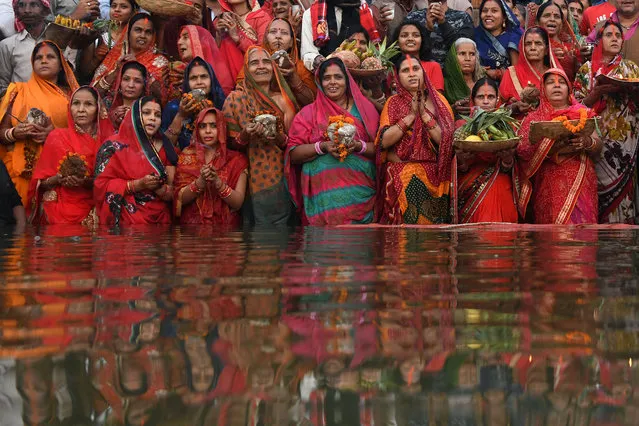 Indian devotees take part in a ritual worshipping the sun god during the Chhath Festival on the banks of the holy river Ganges in Varanasi on November 14, 2018. The Chhath Festival, also known as Surya Pooja, or worship of the sun, is observed in parts of India and Nepal and sees devotees pay homage to the sun and water gods. Devotees undergo a fast and offer water and milk to the sun god at dawn and dusk on the banks of rivers or small ponds and pray for the longivety and health of their spouse. (Photo by Dominique Faget/AFP Photo)