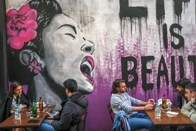 People sit in a restaurant in Kadikoy neighbourhood, in Istanbul, on June 1, 2021, after the country lifted health restrictions measures against the Covid-19 (coronavirus) pandemic in regions with lower infection rates. Businesses are allowed to operate at half-capacity until 10:00 p.m. as coronavirus restrictions are eased. (Photo by Bulent Kilic/AFP Photo)