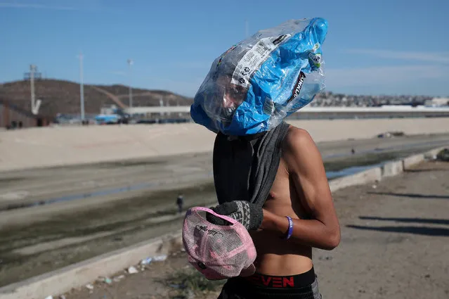 A migrant, part of a caravan of thousands from Central America trying to reach the United States, wears a homemade gasmask as he walks near the border fence between Mexico and the United States in Tijuana, Mexico, November 25, 2018. (Photo by Hannah McKay/Reuters)