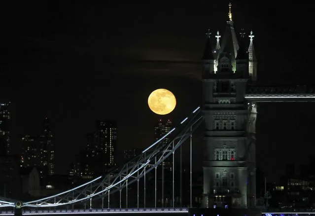 A full moon rises over the high buildings behind Tower Bridge in central London, Monday, March 29, 2021. (Photo by Tony Hicks/AP Photo)