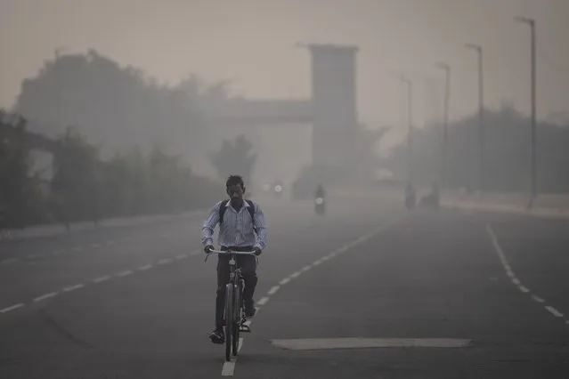 A cyclist rides amid smog in New Delhi, India, Tuesday, November 7, 2023. Masks are back on the streets as residents of the capital city grapple with the annual surge in air pollution that has engulfed the region. (Photo by Altaf Qadri/AP Photo)