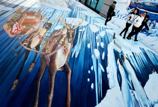 Chinese shoppers walk beside a 3D mural of a snowy winter scene outside of a shopping mall in Beijing on December 13, 2013.  Beijing will bid to hold the 2022 Winter Games with the ice sports held in the city and snow events would take place in the city of Zhangjiakou, in the neighbouring province of Hebei. Other candidate cities for the 2022 Winter Games are Germany's Munich, the Norwegian capital Oslo, Almaty in Kazakhstan, Poland's Krakow, Ukraine's Lviv and Sweden's Oestersund. (Photo by Mark Ralston/AFP Photo)