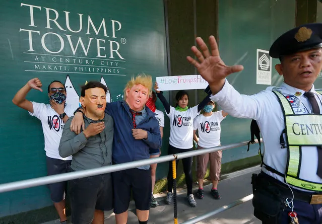 A private security tries to prevent the media from taking pictures as protesters picket the Trump Tower hours after Donald Trump was sworn in as the 45th President of the United States, Saturday, January 21, 2017, in the financial district of Makati city east Manila, Philippines. Pledging emphatically to empower America's “forgotten men and women”, Donald Trump was sworn in as President of the United States on Friday, taking command of a riven nation facing an unpredictable era under his assertive but untested leadership. (Photo by Bullit Marquez/AP Photo)