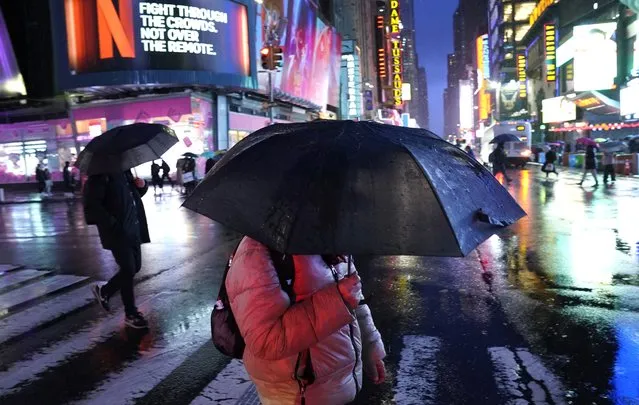 People hold their umbrellas as they walk through Times Square, New York, on January 9, 2024, as the city prepares for a winter storm that could bring flooding to the New York area. (Photo by Timothy A. Clary/AFP Photo)