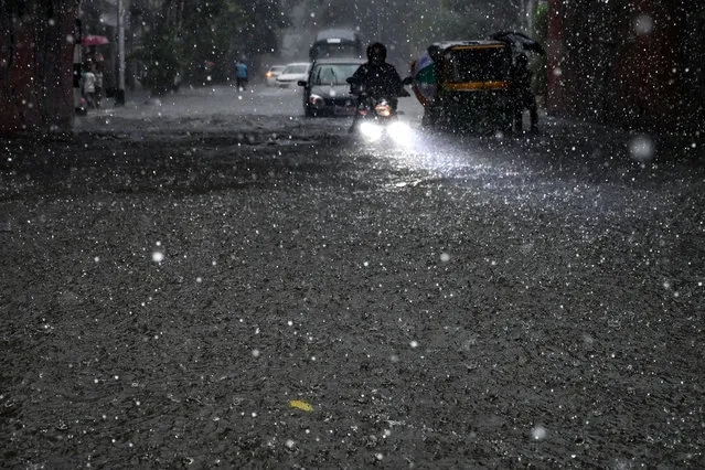 Motorists make their way through a waterlogged street amid heavy rainfall in Kolkata on September 20, 2021 reportedly triggered by cyclonic circulation formed over the Bay of Bengal. (Photo by Dibyangshu Sarkar/AFP Photo)