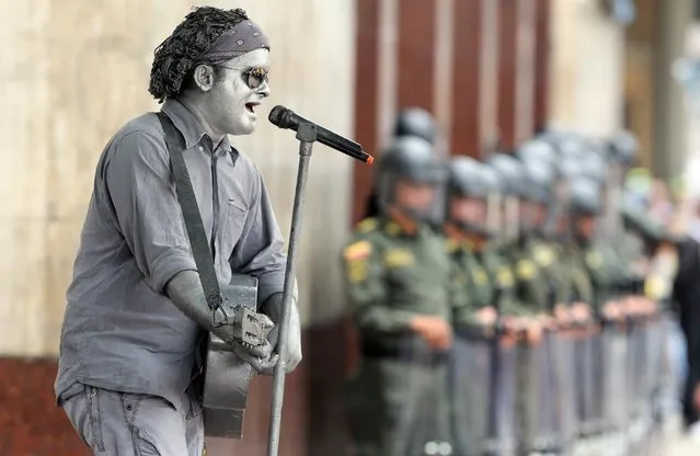 A silver street performer dressed as Colombian singer Carlos Vives sings during a May Day march in Bogota, Colombia, Friday, May 1, 2015. Left-wing groups, governments and trade unions were staging rallies around the world Friday to mark International Workers Day also known as May Day. (Photo by Fernando Vergara/AP Photo)