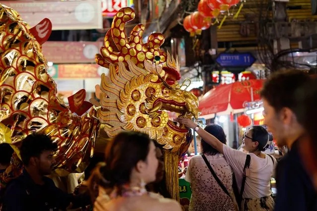 Dancers carry a Chinese dragon as people offer money during Lunar New Year's Eve in Bangkok, Thailand, on February 8, 2024. (Photo by Jorge Silva/Reuters)