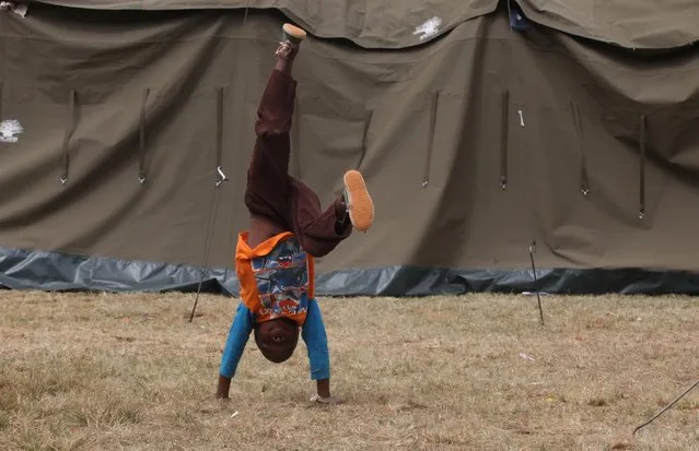 A child does a handstand outside a tent at a shelter for victims of immigrant attacks in Johannesburg, Wednesday, April 22, 2015. (Photo by Denis Farrell/AP Photo)