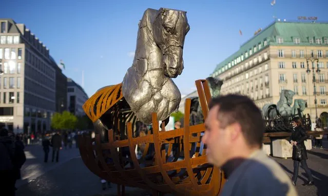 A man walks past one of 20 horses that make up a travelling art exhibition called “Lapidarium” by Mexican artist Gustavo Aceves, near Brandenburg Gate in Berlin, Germany, May 4, 2015. (Photo by Hannibal Hanschke/Reuters)