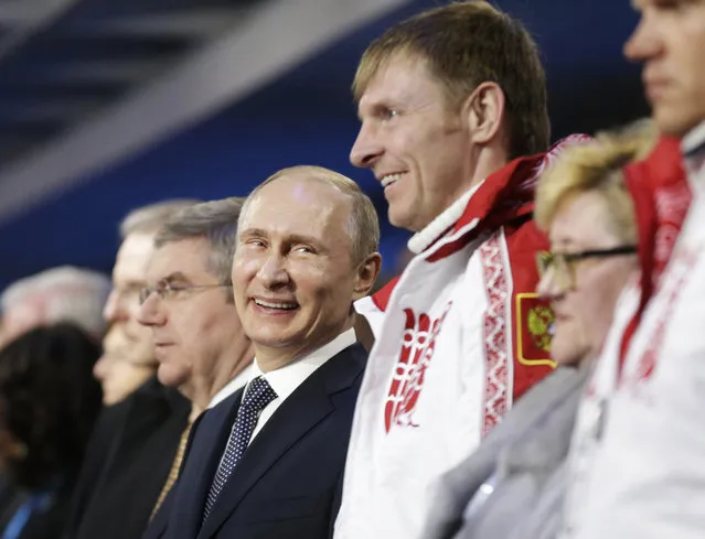 Russian President Vladimir Putin (C) stands next to Alexander Zubkov, gold medalist in the two-man and four-man bobsleigh for Russia, during the Closing Ceremony of the Sochi Winter Olympics at the Fisht Olympic Stadium on February 23, 2014. (Photo by David Goldman/AFP Photo)