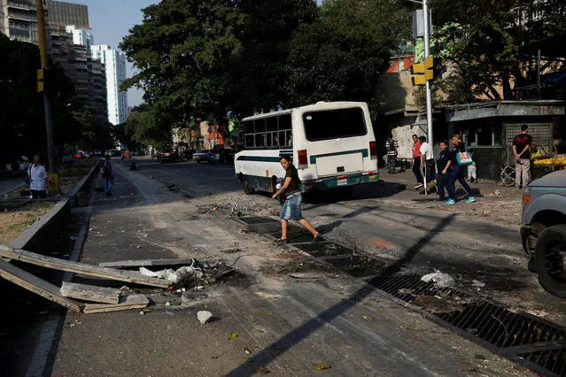 People walk past debris on a street after a protest in Caracas, Venezuela April 1, 2019. (Photo by Carlos Garcia Rawlins/Reuters)