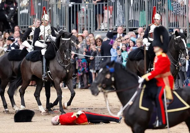 A guard lies on the ground after falling off his horse during the Trooping the Colour parade in central London, Britain on June 8, 2019. (Photo by Peter Nicholls/Reuters)