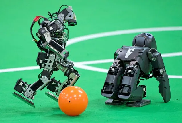 A robot of a German team, left, plays the ball besides a British team robot in the Kids League at the RoboCup German Open 2014 in Magdeburg, Germany, Thursday, April 3, 2014. 44 international RoboCup Major League teams from 12 countries demonstrate the state-of-the-art competitions in soccer, rescue and service robots. The RoboCup German Open takes place from April 3 to April 5, 2014. (Photo by Jens Meyer/AP Photo)