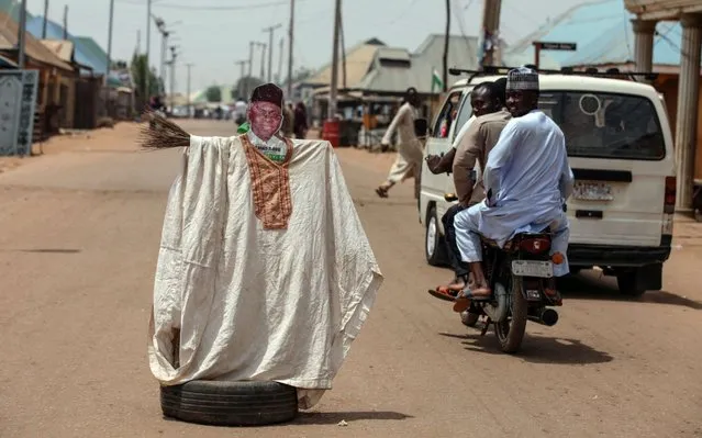 People pass by an effigy depicting the incumbent governor of the Kaduna State, Mallam Nasir El-Rufai, during Nigeria’s governorship and state assembly elections in Kaduna on March 9, 2019. For the second time in a fortnight, Nigerians went to the polls to elect governors in 29 of Nigeria's 36 states, all state assemblies and administrative councils in the Federal Capital Territory of Abuja. The Independent National Electoral Commission (INEC) is expected to announce the results in a few days. (Photo by Kula Sulaimon/AFP Photo)