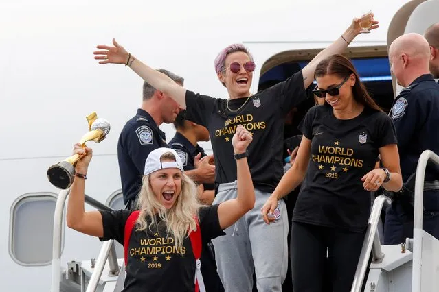 U.S. soccer players Julie Ertz (L), Megan Rapinoe (C) and Alex Morgan celebrate as they exit the plane with the Trophy for the FIFA Women's World Cup while the U.S team arrive at the Newark International Airport, in Newark, New Jersey, U.S., July 08, 2019. (Photo by Eduardo Munoz/Reuters)