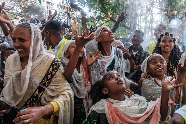 Ethiopian Orthodox worshippers get sprinkled with water in the compound of Fasilides Bath during the celebration of Timkat, the Ethiopian Epiphany, in the city of Gondar, Ethiopia, on January 19, 2022. (Photo by Eduardo Soteras/AFP Photo)