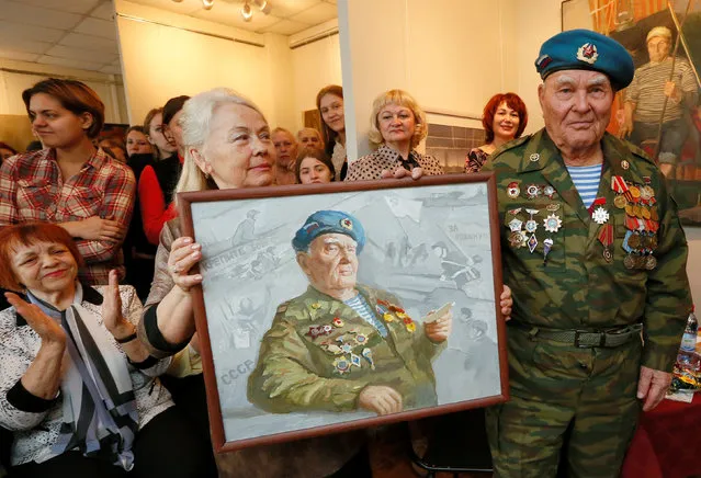 Georgy Ivkin, 91, former airborne troops soldier and World War Two veteran, stands near an oil painting, a portrait of himself created by a student of Krasnoyarsk Art College as a present for the upcoming Victory Day, during a meeting in Krasnoyarsk, Siberia, Russia, April 28, 2016. (Photo by Ilya Naymushin/Reuters)