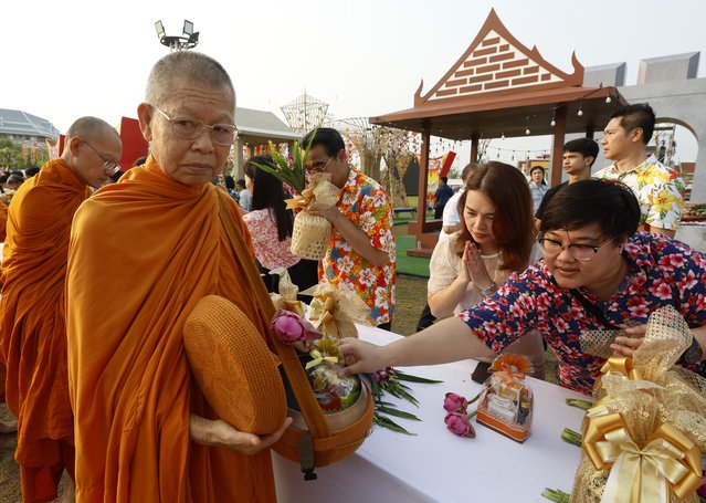 Thais make a merit by offering food to a Buddhist monk during the morning alms as a religious merit making rite to mark the Thai traditional New Year known as “Songkran”, at Sanam Luang Royal Ground in Bangkok, Thailand, 13 April 2024. Thailand celebrates the Thai traditional New Year 'Songkran' festival, also known as the water festival, which annually falls on 13 April, and is celebrated with splashing water as a symbolic sign of cleansing and washing away the sins and bad luck from the old year. The United Nations Educational, Scientific, and Cultural Organization (UNESCO) inscribed Thailand's Songkran Festival in the list of the Intangible Cultural Heritage of Humanity. (Photo by Narong Sangnak/EPA)