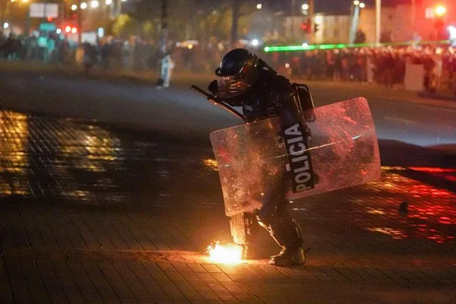 A riot policeman puts out a fire during a protest demanding government action to tackle poverty, police violence and inequalities in healthcare and education systems, in Bogota, Colombia, May 10, 2021. (Photo by Nathalia Angarita/Reuters)