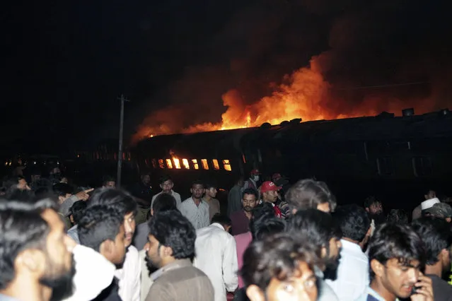 People look at a burning passenger train in Shaikhupura, near Lahore, Pakistan, early Tuesday, March 28, 2017. Authorities in Pakistan say a passenger train has collided with an oil tanker truck, killing at least one person and injuring others. (Photo by K.M. Chaudary/AP Photo)