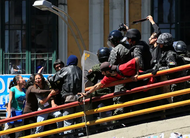 Demonstrators clash with riot police on a pedestrian bridge during a rally protest of people with physical disability demanding the government to increase their monthly disability subsidy, in La Paz, Bolivia, May 3, 2016. (Photo by David Mercado/Reuters)
