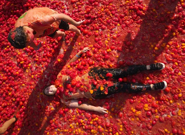 People lay in tomato pulp as they take part in the first Russian Tomatina battle in St. Petersburg, Russia, Sunday, August 18, 2019. (Photo by Dmitri Lovetsky/AP Photo)