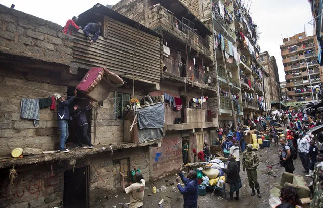 Residents lower furniture down to the street as they and others are evicted from their apartment blocks close to the site of last week's building collapse, after their homes were deemed unfit for habitation and marked for demolition, in the Huruma neighborhood of Nairobi, Kenya, Friday, May 6, 2016. (Photo by Ben Curtis/AP Photo)