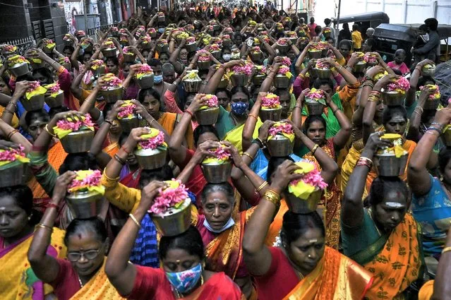 Hindu devotees carry urns containing milk on their head during a procession on the occasion the Panguni Uthiram festival, which is observed in the Tamil month of Panguni and is celebrated to honour the Hindu God Murugan, in Chennai on March 18, 2022. (Photo by Arun Sankar/AFP Photo)