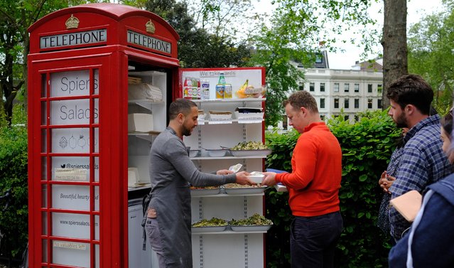 Ben Spiers serves a customer as he works at his salad bar which is based in a British red telephone box near the British Museum in London, Tuesday, May, 17, 2016. Ben also works part time as a lawyer, and works the salad bar two days a week at lunch time as he starts the business up in this iconic and unusual setting. (Photo by Alastair Grant/AP Photo)