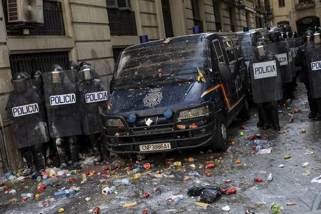 Spanish police stand outside a police station surrounded of objects thrown by pro-independence demonstrators in Barcelona, Spain, Friday, October 18, 2019. Various flights into and out of the region are cancelled Friday due to a general strike called by pro-independence unions and five marches of tens of thousands from inland towns are expected converge in Barcelona's center on Friday afternoon for a mass protest with students to and workers who are on strike. (Photo by Bernat Armangue/AP Photo)