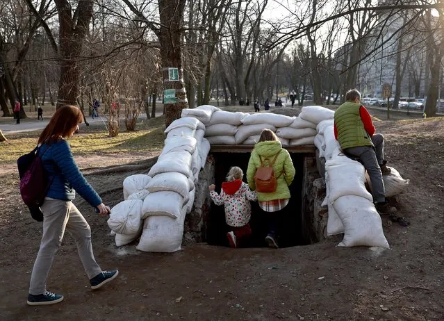 People walk down the sandbagged entrance to a bomb shelter after air raid sirens sounded on March 25, 2022 in Lviv, Ukraine. Lviv has served as a stopover and shelter for the millions of Ukrainians fleeing the Russian invasion, either to the safety of nearby countries or the relative security of western Ukraine. (Photo by Joe Raedle/Getty Images)